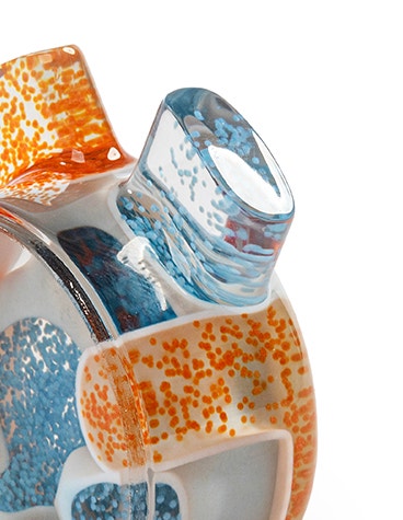 Vista superior de un mezclador estático impreso en 3D, transparente en su mayor parte y con algunas partículas naranjas y azules en su interior