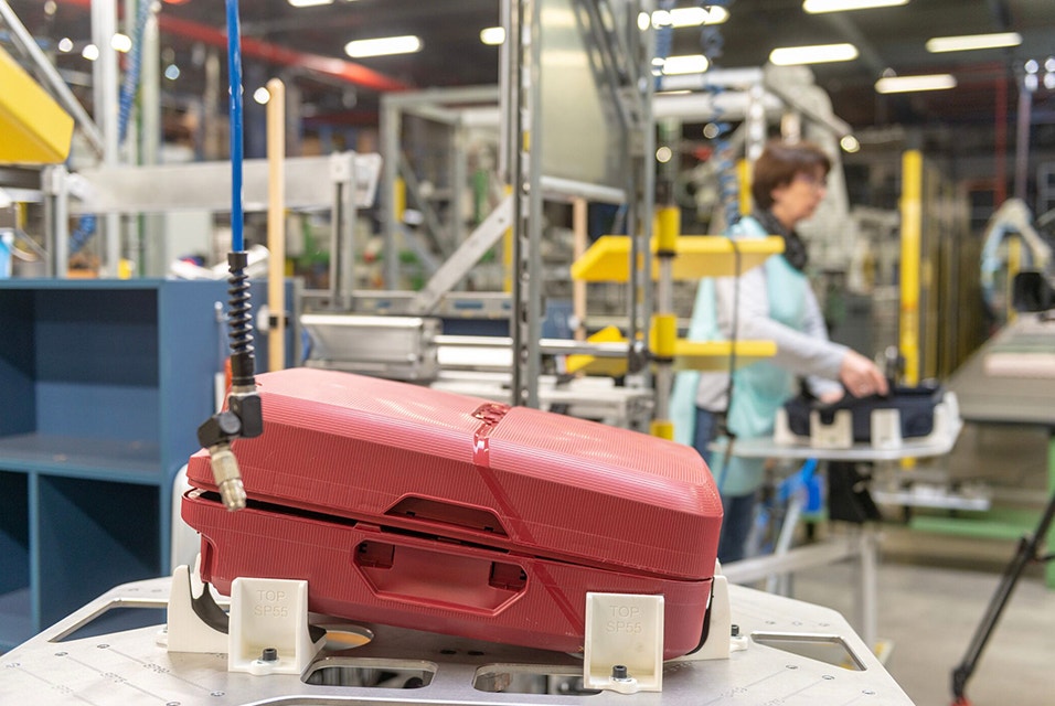A red Samsonite suitcase secured in a jig