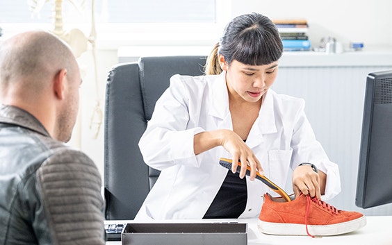 Doctor placing an insole in a shoe in front of her patient