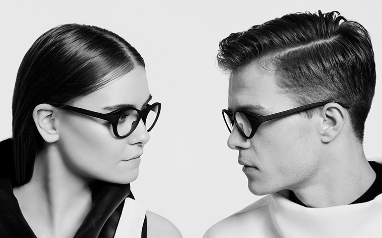 Immagine in bianco e nero di due modelli che si guardano tra loro e indossano occhiali neri Hoet Cabrio