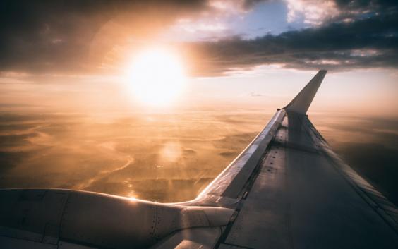 Blick auf einen Sonnenuntergang und einen Flugzeugflügel aus dem Inneren des Flugzeugs