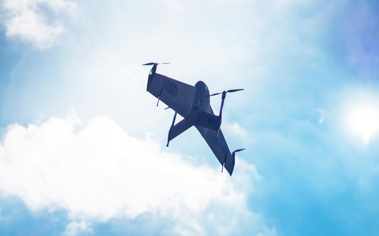 Un plano del dron Marlyn impreso en 3D en vuelo contra un cielo azul con nubes blancas.