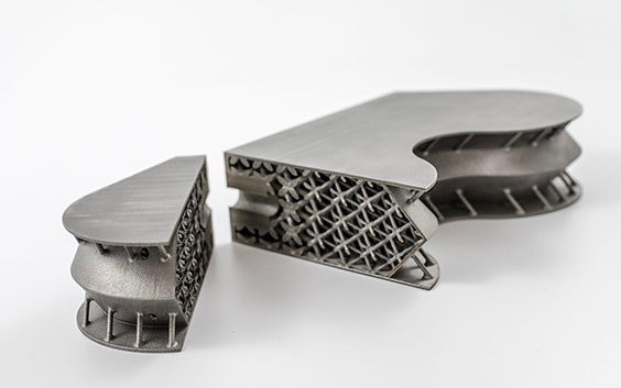 Componente aerospaziale stampato 3D in titanio, aperto per mostrare una sezione trasversale di strutture reticolari
