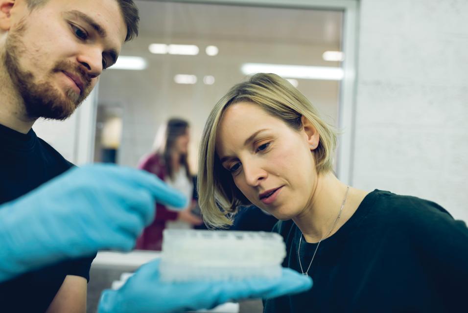 Man showing a 3D-printed part to a woman