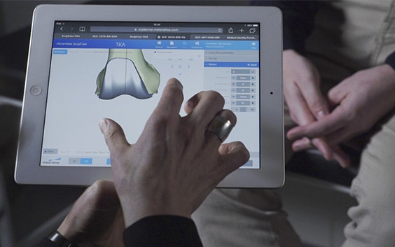 Hände berühren einen Touchscreen mit einem 3D-Modell eines Knochens