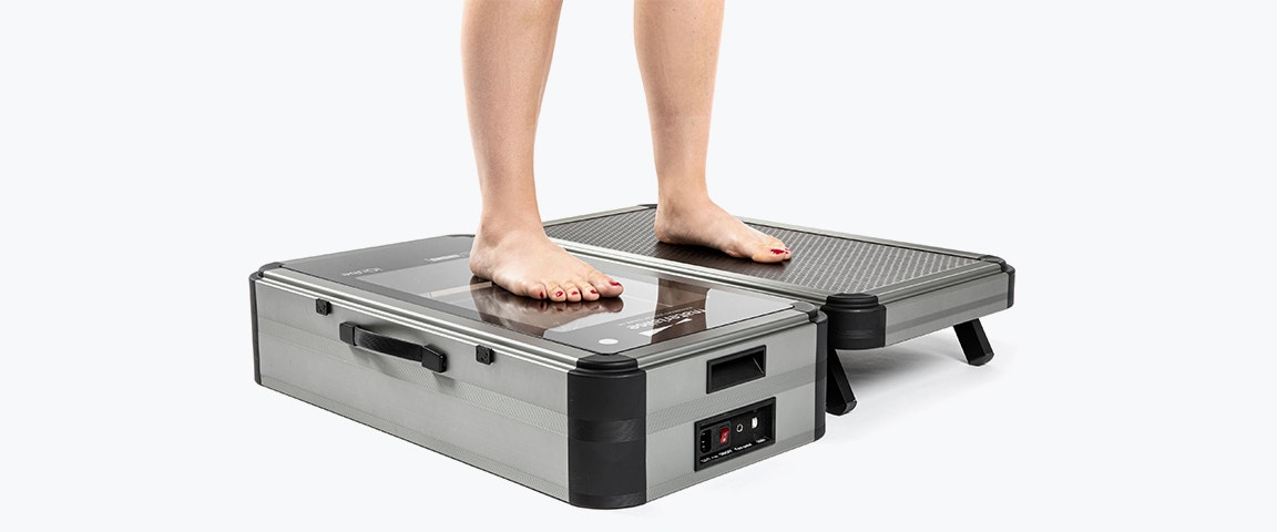 Person standing with one foot on the iQube E500 scanner and one foot on a platform