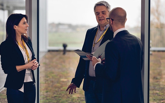 One woman and two men talking in business attire