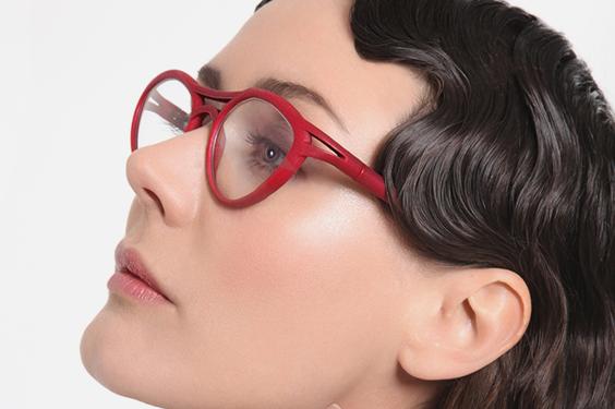 Female model with wavy hair wearing red eyeglasses with her head tilted up