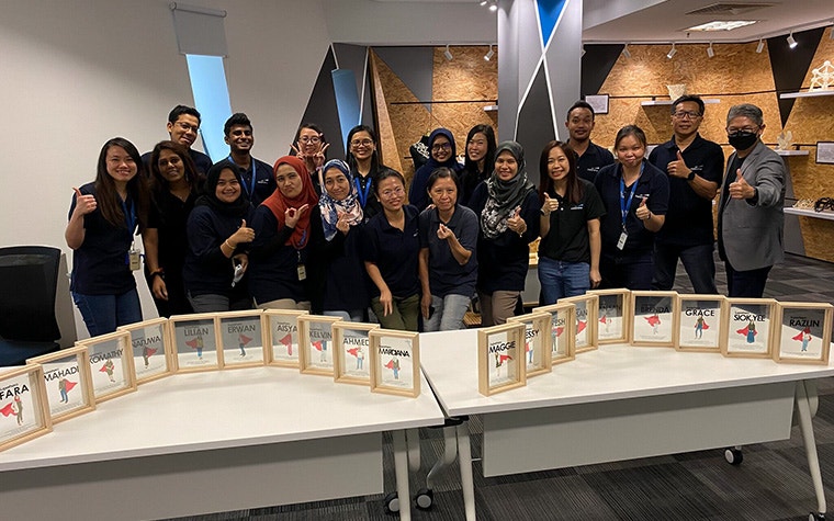 A group photo of Materialise Malaysia employees posing in front of several awards