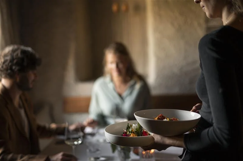 Waitress serves two dishes in a restaurant while a couple is seated at the table.