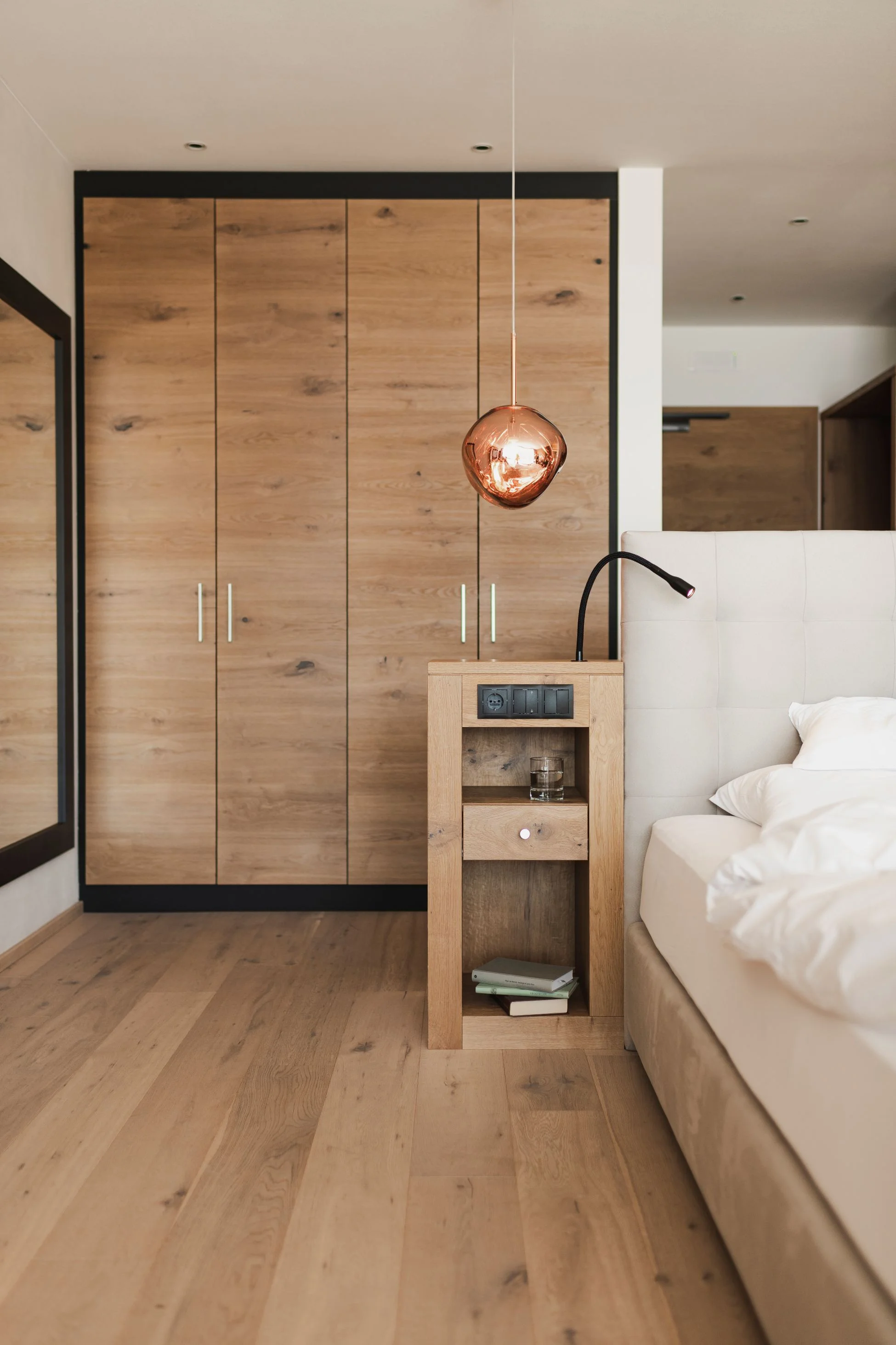 Gemütliches Hotelzimmer in Südtirol mit Einrichtung aus Naturholz, Nachttisch und modernem Doppelbett