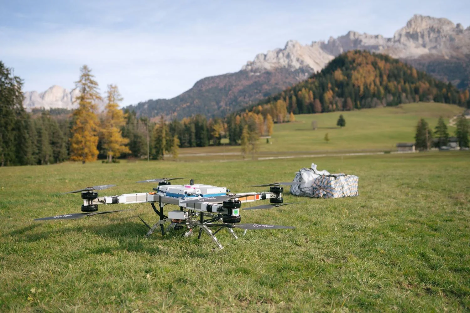 Landed cargo drone with transported goods on a meadow, with the Dolomites in the background