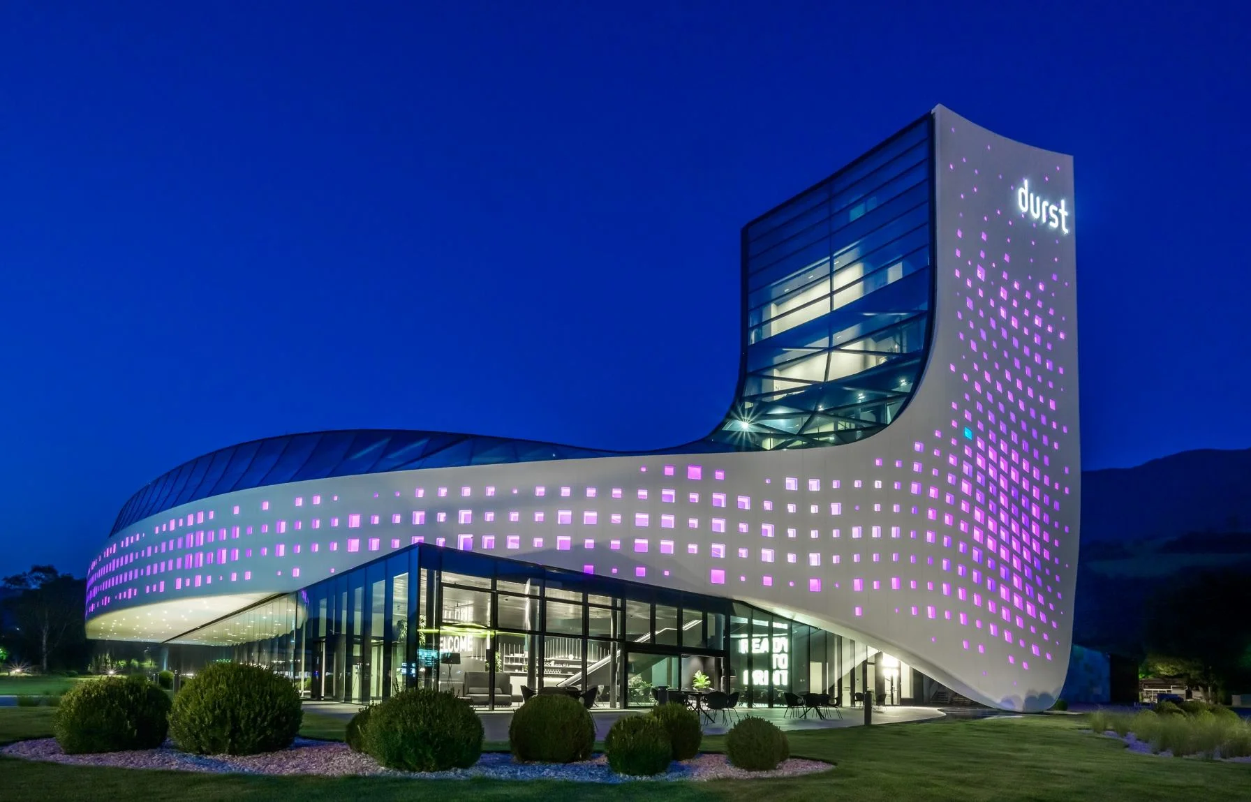 Illuminated modern company building of Durst during the blue hour