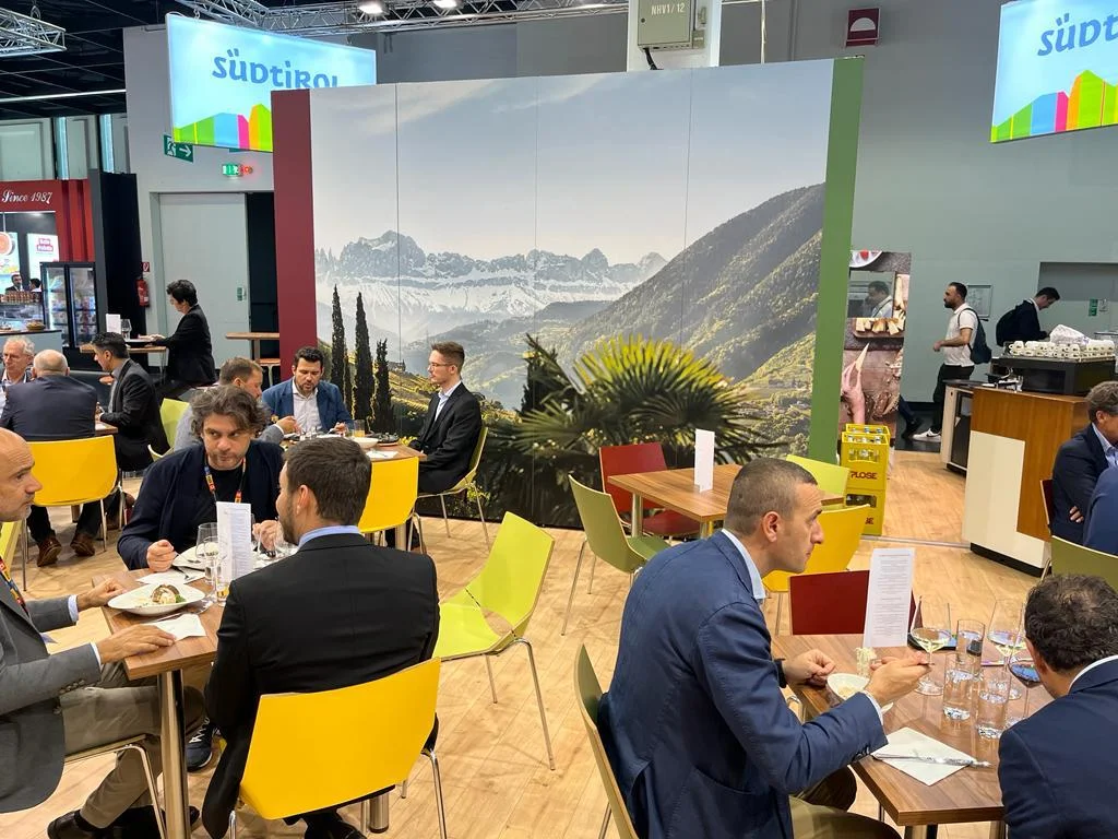 Visitors at tables in conversation at the trade fair booth under the South Tyrol brand