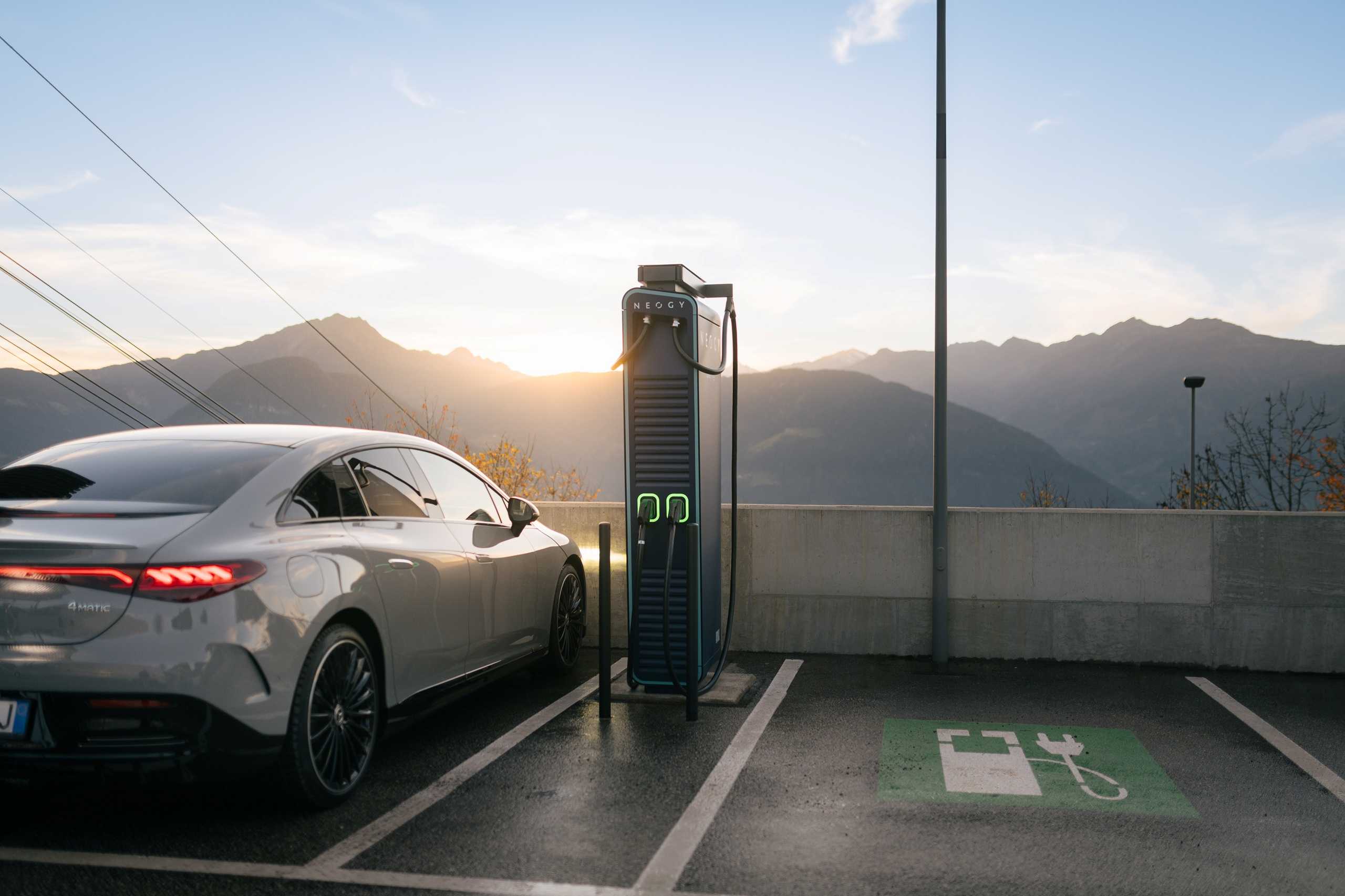 Parked luxury car at an electric charging station, next to it a free parking space with charging station icon