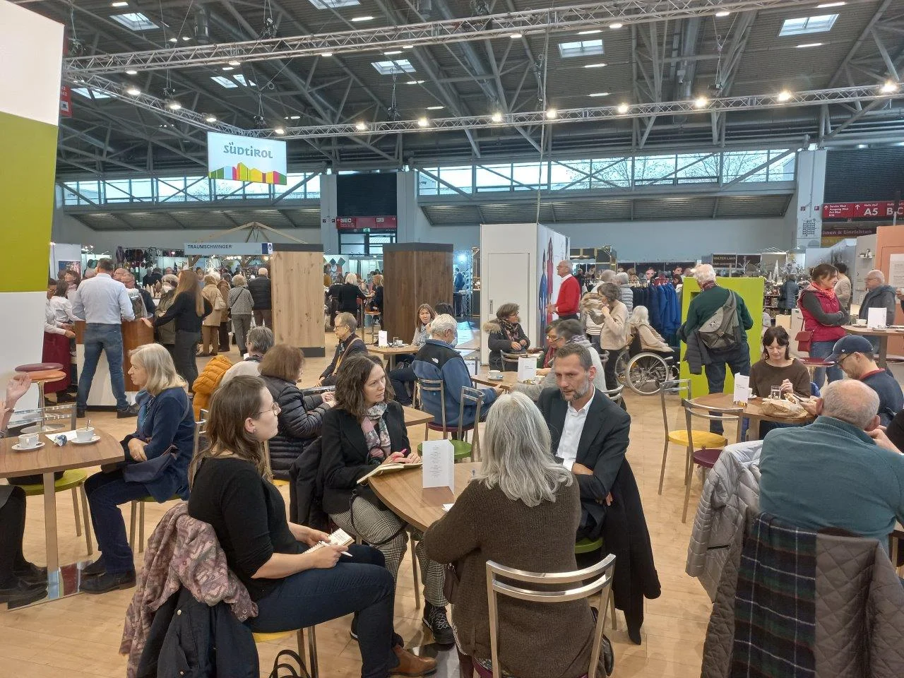 Numerous visitors sitting at tables in an exhibition hall