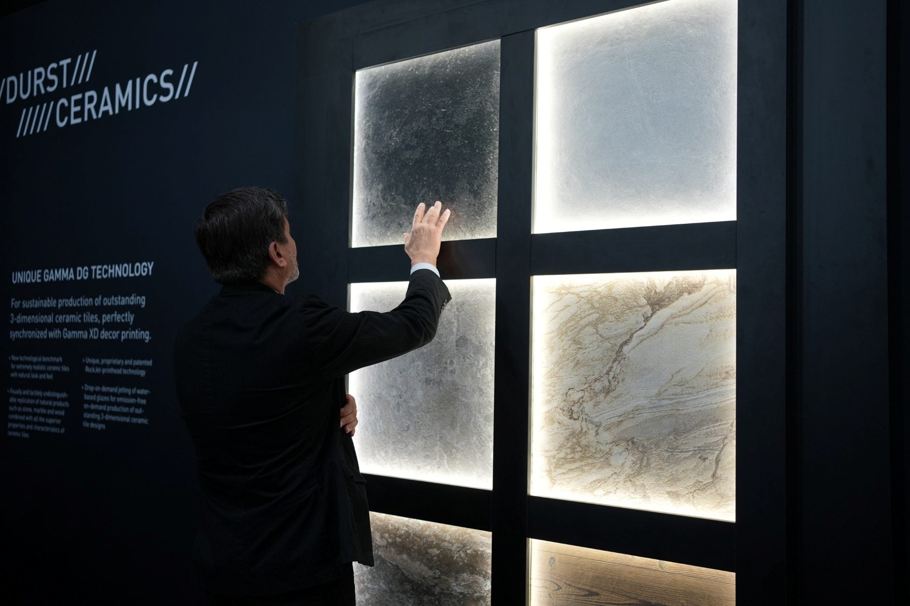 Man in suit touching a display surface showing different tile prints