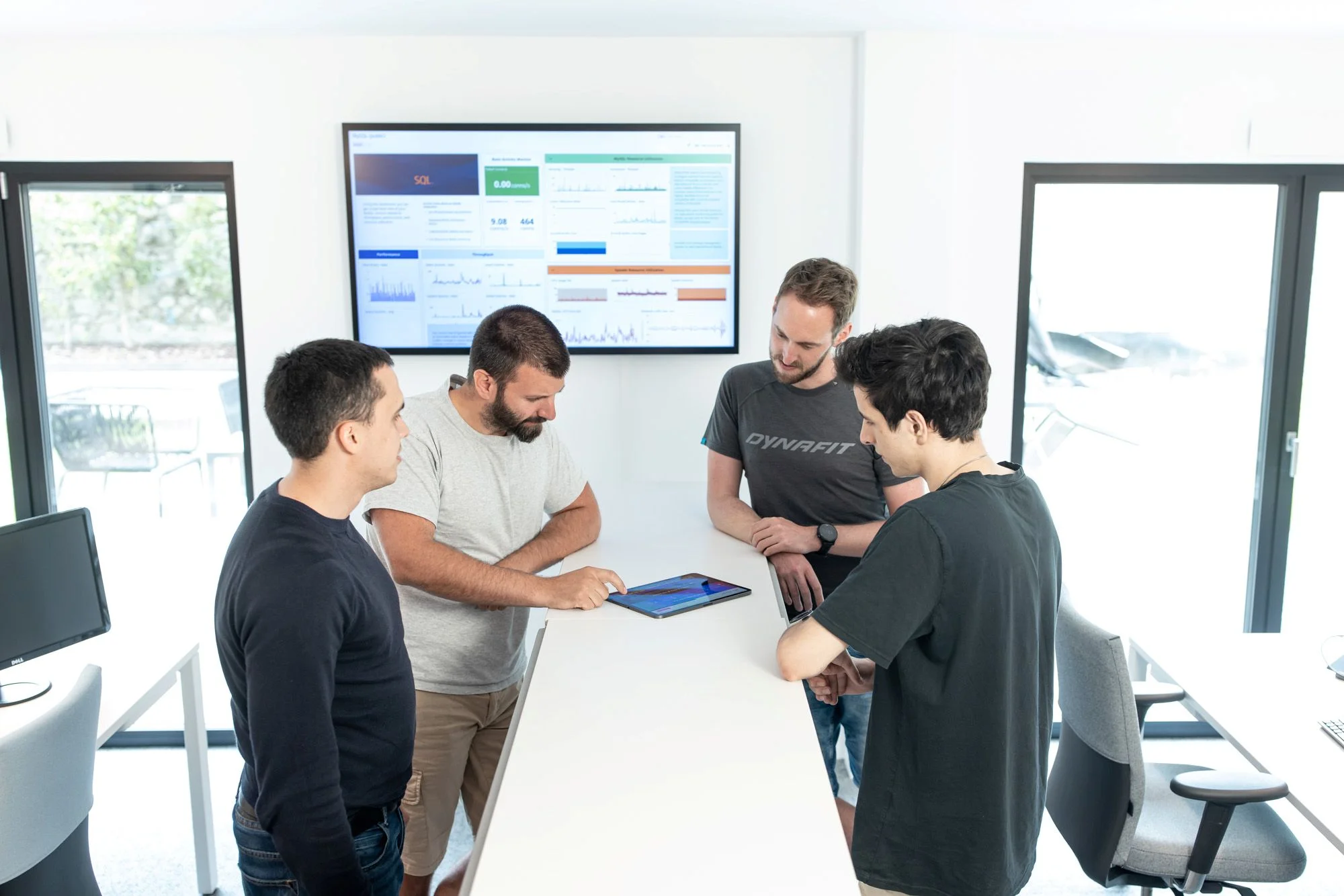 Four young employees in office in front of screen with chart