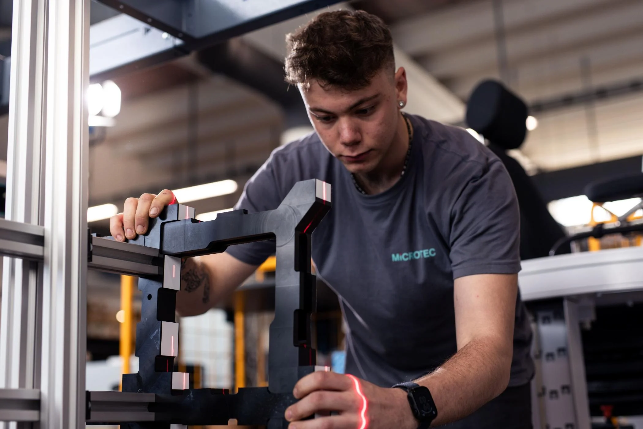 Young employee operating a laser device in a modern production hall