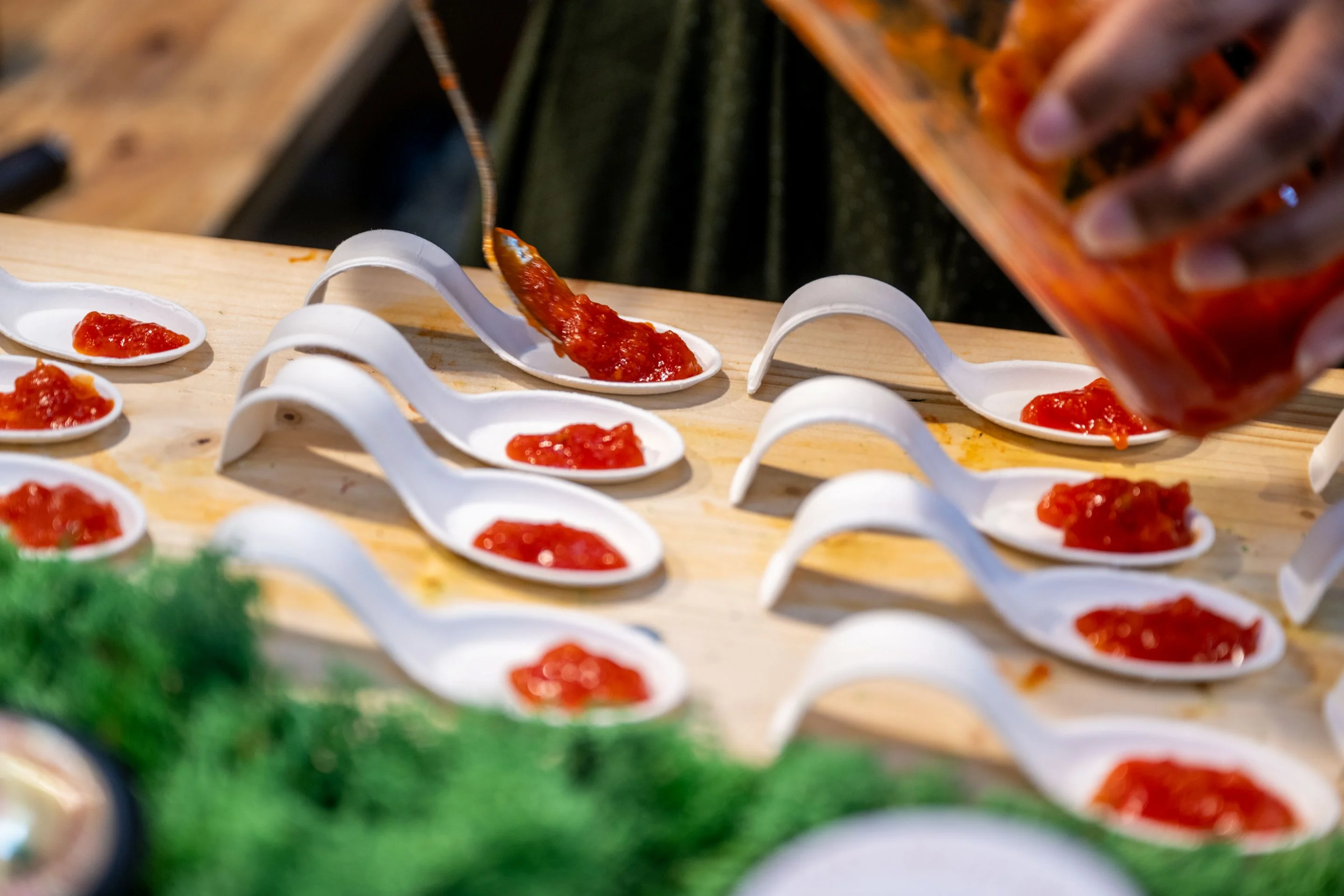 Several tasting spoons being filled with red sauce