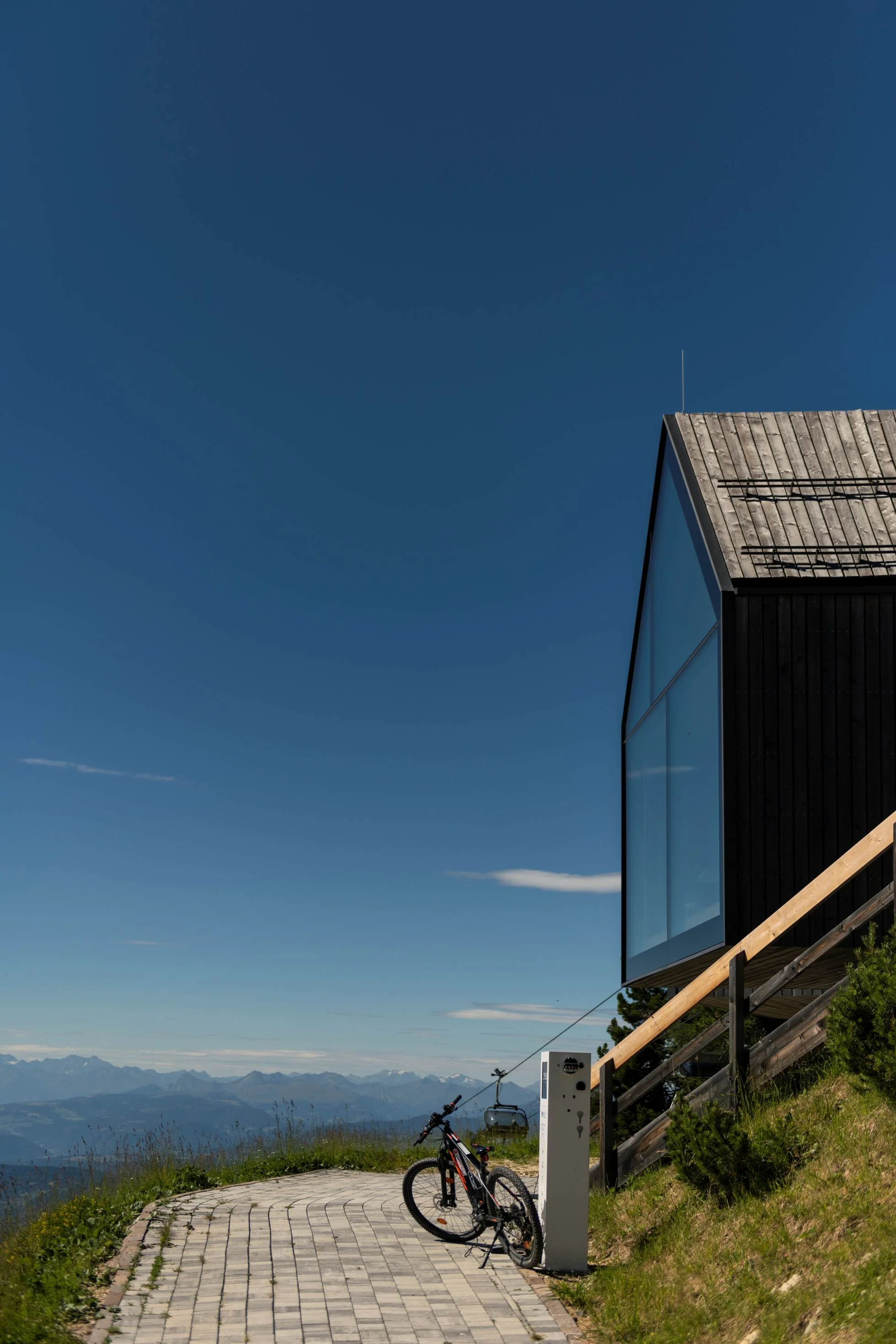 Fahrrad neben moderner Panoramastruktur in den Bergen mit Blick auf die Dolomiten in Südtirol