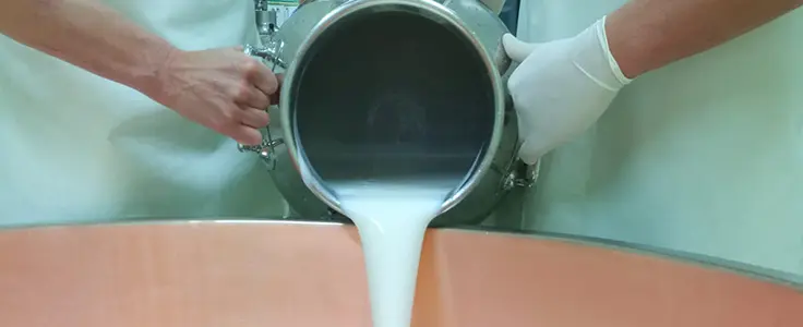 Milch wird in einen Kessel geschüttet Milch wird in einen Kessel geschüttet