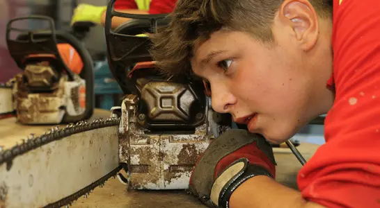 Schüler begutachtet seine Motorsäge. Schüler begutachtet seine Motorsäge.