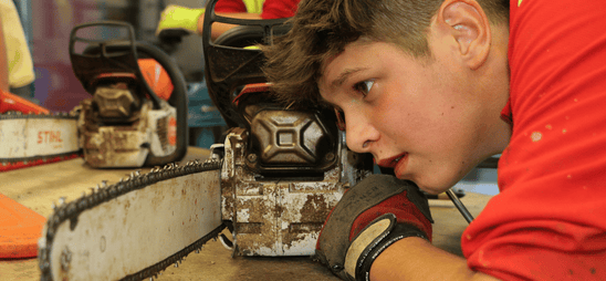 Schüler begutachtet seine Motorsäge. Schüler begutachtet seine Motorsäge.