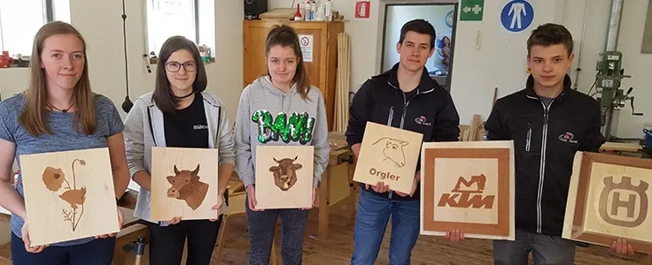 Schülerinnen und Schüler halten ihre Abschlusswerke in die Kamera Schülerinnen und Schüler halten ihre Abschlusswerke in die Kamera