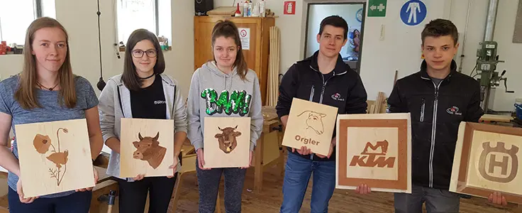 Schülerinnen und Schüler halten ihre Abschlusswerke in die Kamera Schülerinnen und Schüler halten ihre Abschlusswerke in die Kamera