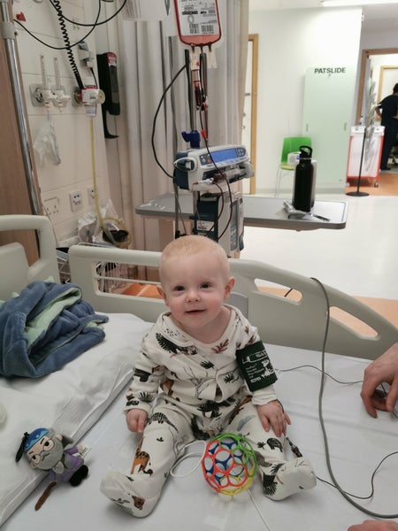 Oliver dressed in pyjamas sitting on a hospital bed