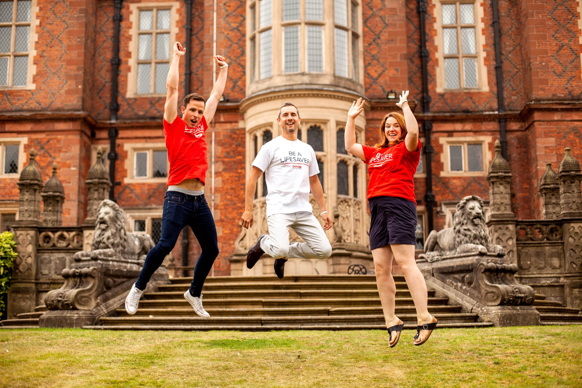 Three people jumping outside Crewe Hall