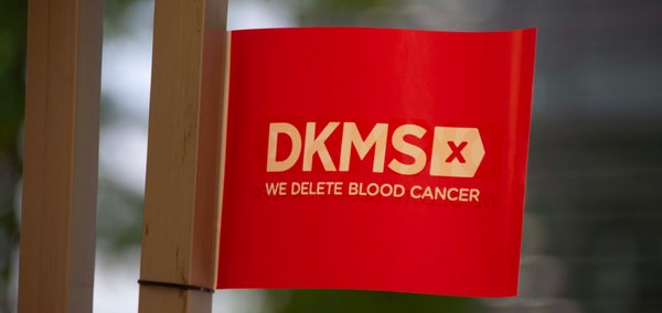 Red flag showing white DKMS logo and tagline 'We delete blood cancer'