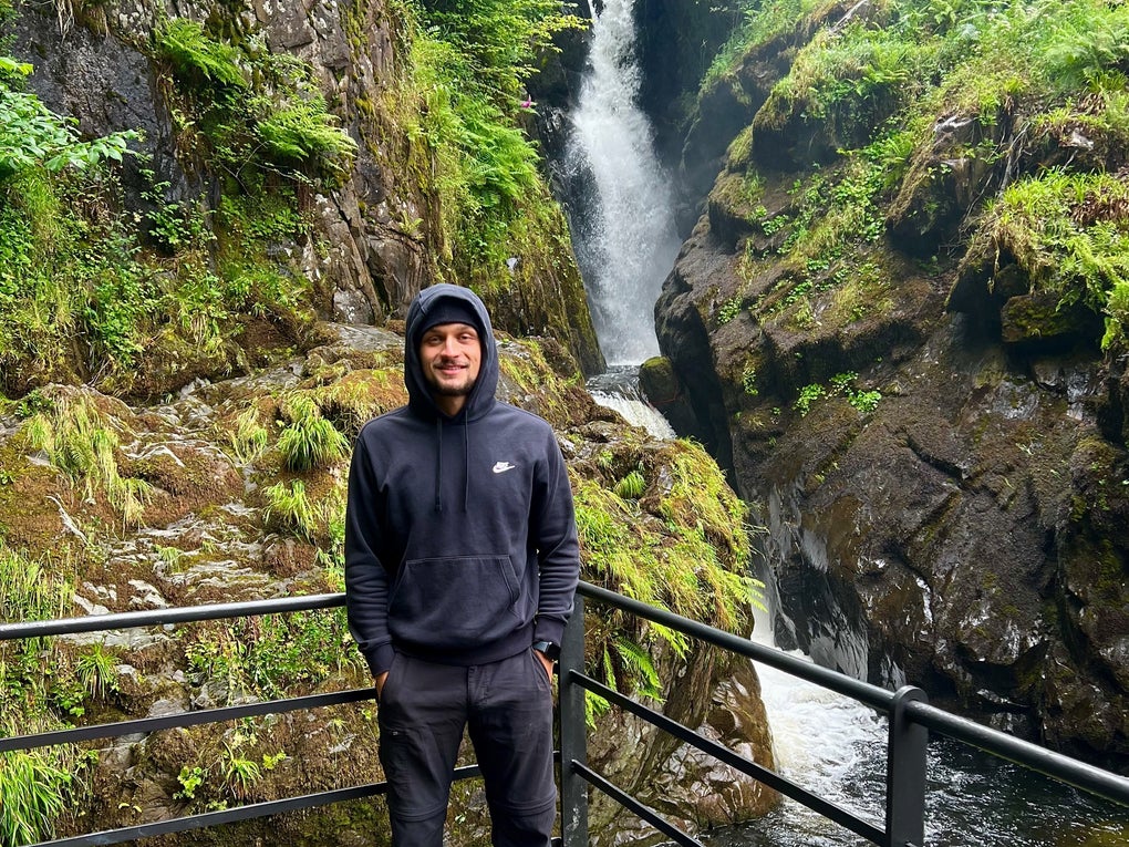 Man in a sweatshirt standing in front of a waterfall Man in a sweatshirt standing in front of a waterfall