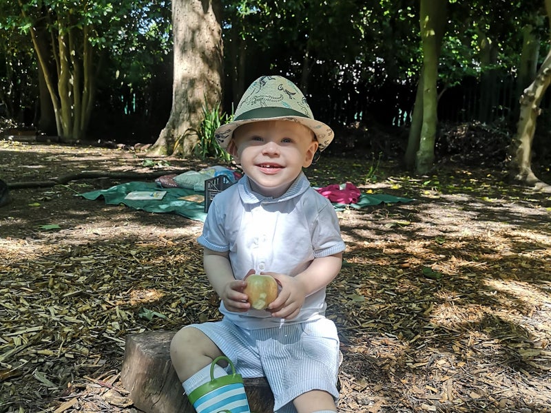 Oliver sitting on the ground in woodland