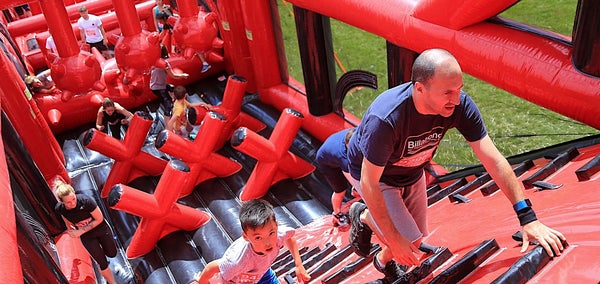 Man and child climbing inflatable obstacle course