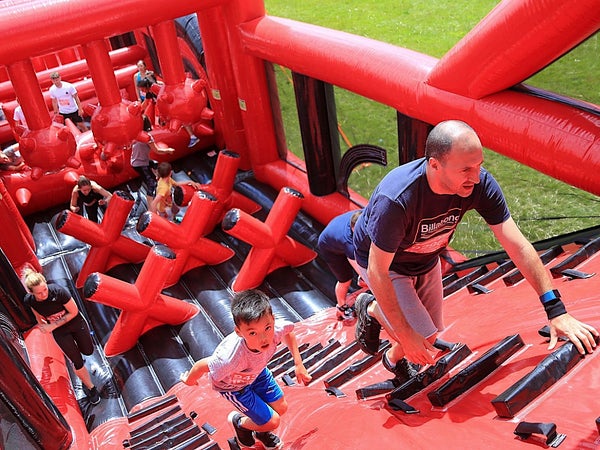 Man and child climbing inflatable obstacle course