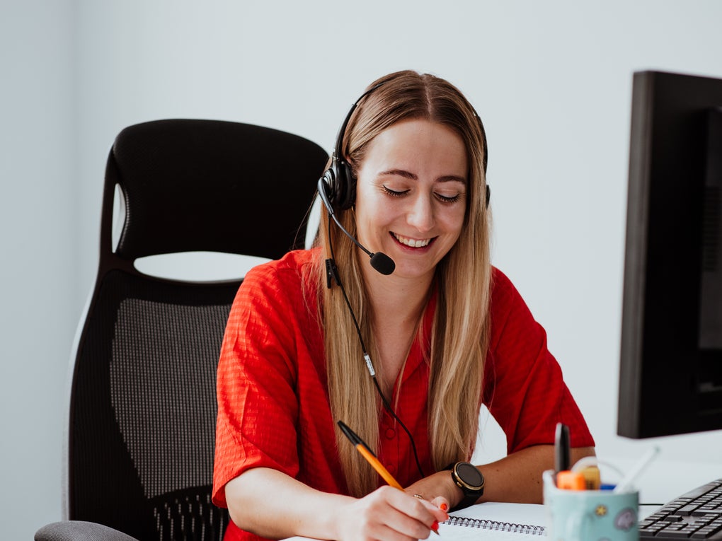 Person wearing a headset taking notes Person wearing a headset taking notes