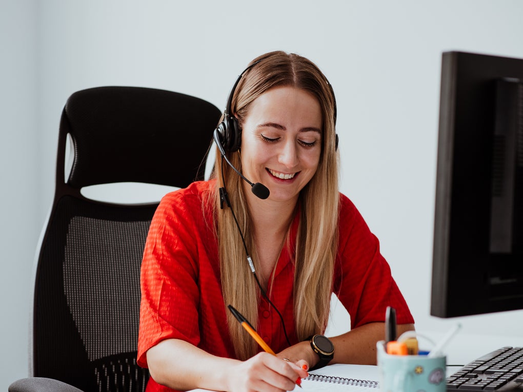 Person wearing a headset taking notes Person wearing a headset taking notes