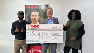The CEO of DKMS holding up the cheque for RCNF partnership grant together with two team members