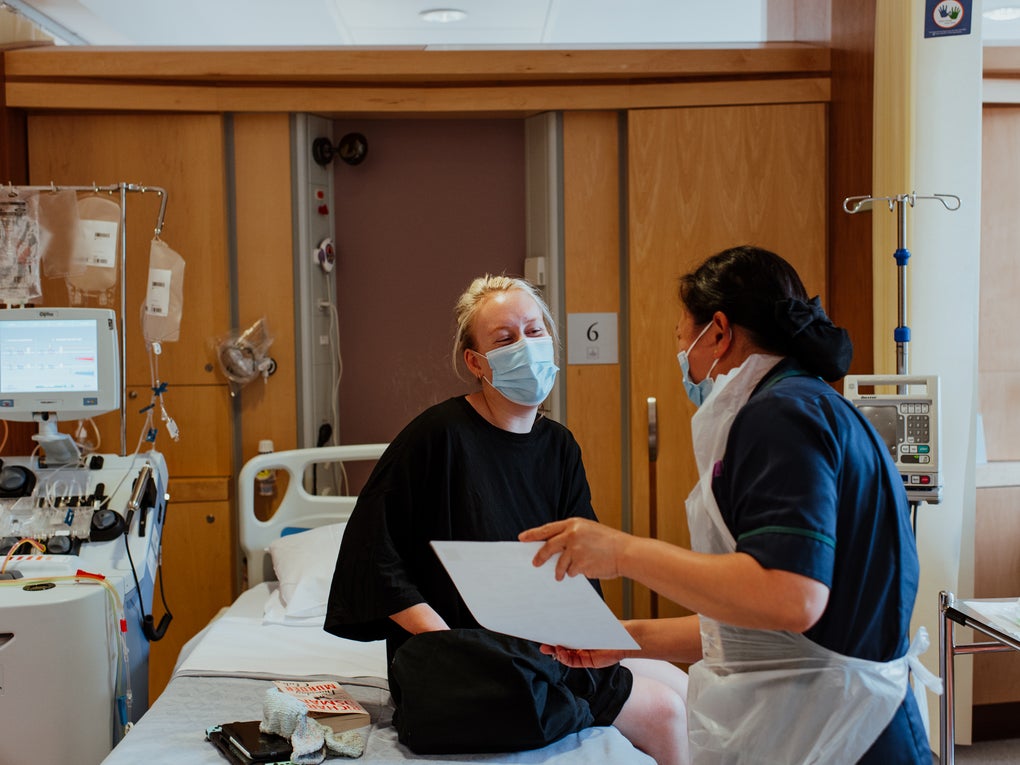 A donor sat on a hospital bed with a nurse showing them a form A donor sat on a hospital bed with a nurse showing them a form