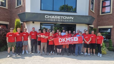 Chasetown Civil Engineering staff outside ther offices wearing DKMS T-shirts and holding a DKMS banner