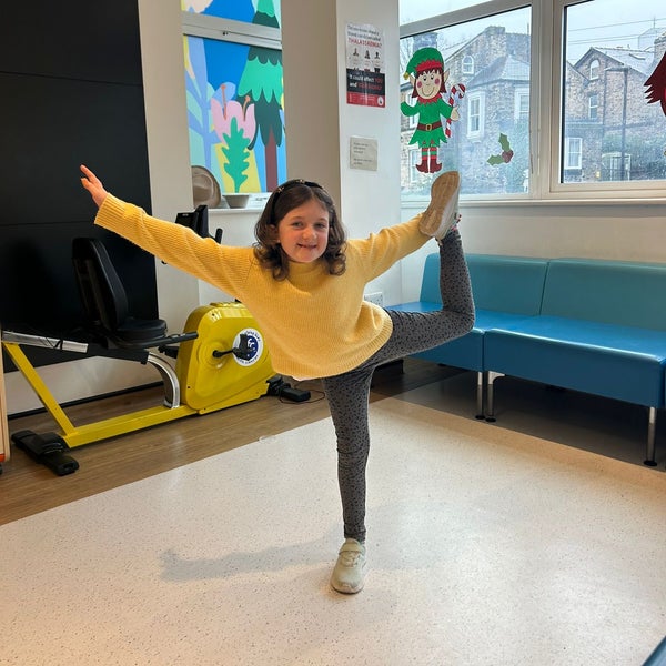 A little Girl dances in a waiting area. She is smiling and standing on one leg. A little Girl dances in a waiting area. She is smiling and standing on one leg.