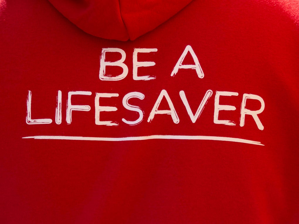 Back of red DKMS hoodie with 'Be a lifesaver' caption in white Back of red DKMS hoodie with 'Be a lifesaver' caption in white