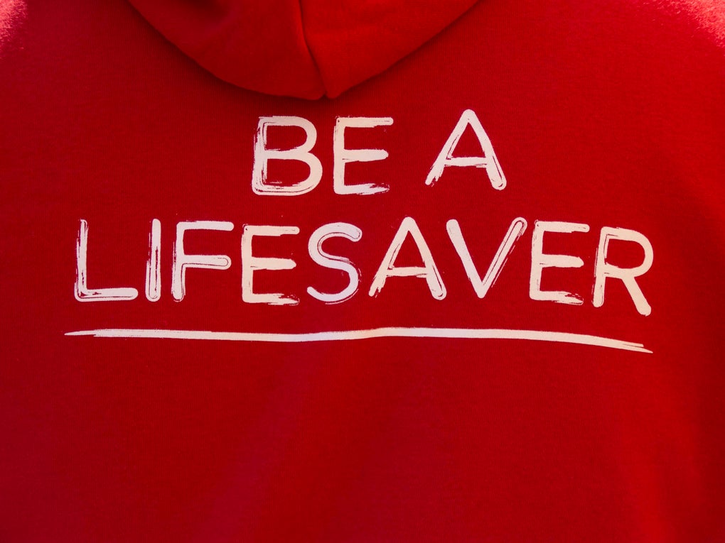 Back of red DKMS hoodie with 'Be a lifesaver' caption in white Back of red DKMS hoodie with 'Be a lifesaver' caption in white
