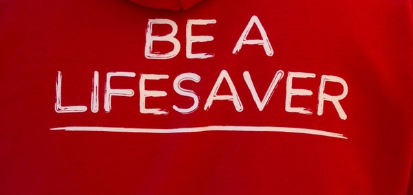 Back of red DKMS hoodie with 'Be a lifesaver' caption in white