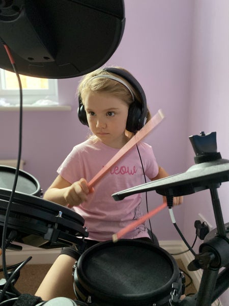 Emilia wearing hedphones practising on a drum kit