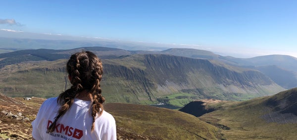 Woman in DKMS top on top of mountain