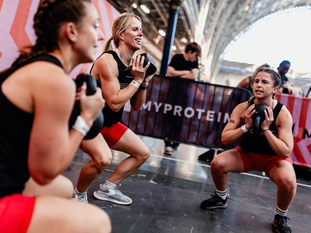 Three women squatting kettlebells Three women squatting kettlebells