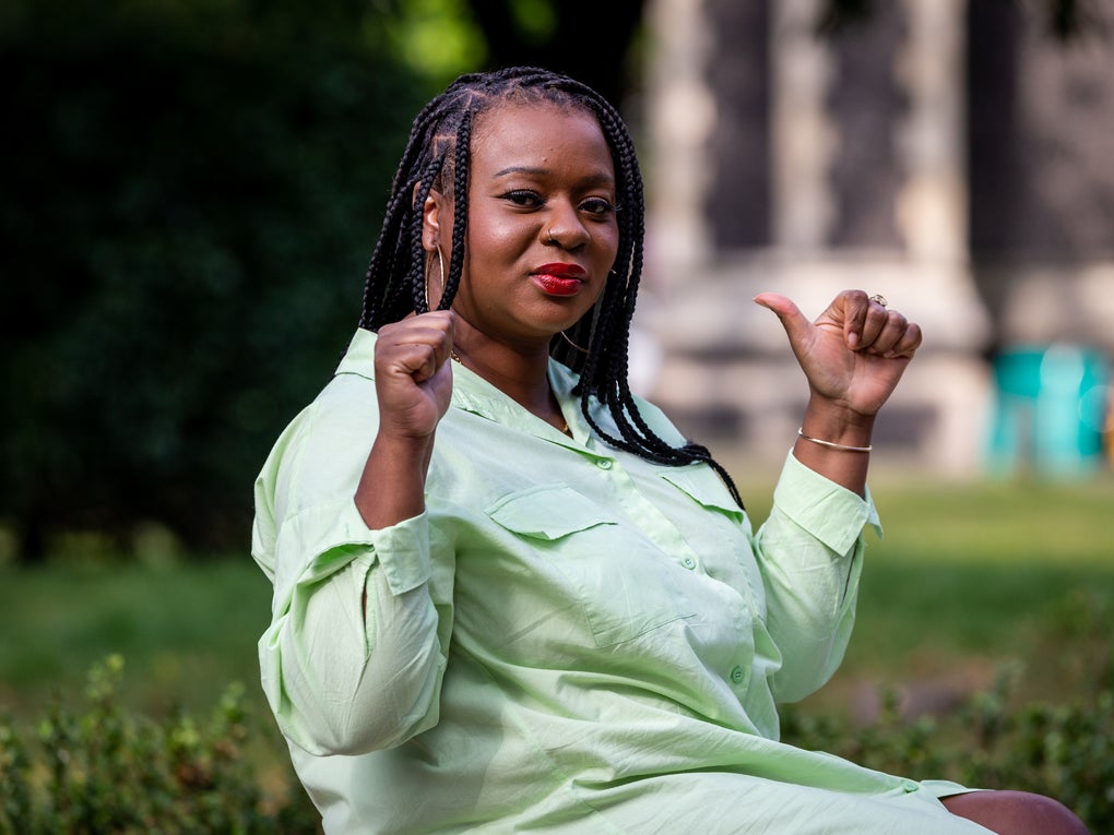 Image of a black woman  with her thumbs up sitting in a park Image of a black woman  with her thumbs up sitting in a park